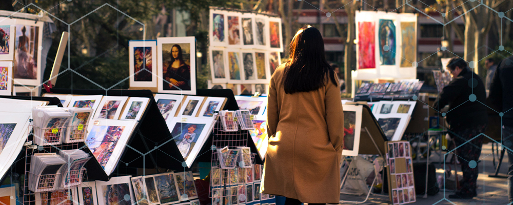 mulher passa por uma calçada com vários quadros expostos