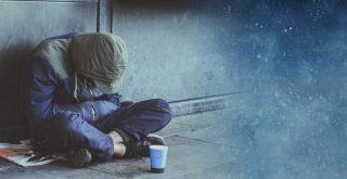 pessoa vulnerável sentada no chão com a cabeça baixa