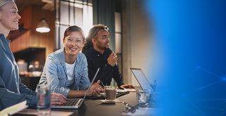 duas mulheres e um homem com notebooks dividem espaço de trabalho